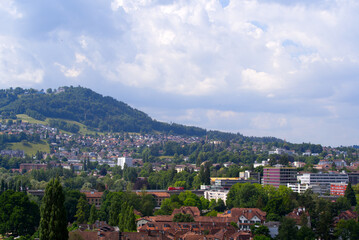 Fototapeta na wymiar Scenic view of City of Bern with local mountain Gurten in the background on a blue cloudy summer day. Photo taken June 16th, 2022, Bern, Switzerland.