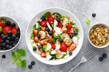 Fruit and berry salad with fresh strawberry, blueberry, banana, cottage cheese and granola with almond. Healthy food, diet breakfast