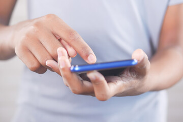 Close up of young man hand using smart phone.