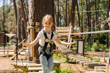 adventure climbing high wire park - children on course rope park. Portrait of cute little girl walk...