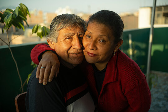 Mature latin married couple posing in front of camera while hugging each other with lots of love