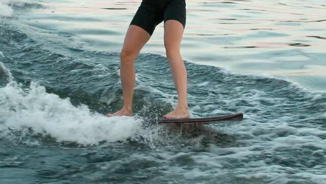 A female surfer jumping on a wakeboard. An experienced wakeboarder splashes water drops into the camera.