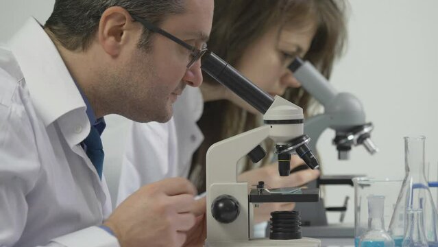 Couple of scientists looking into the microscopes in the laboratory