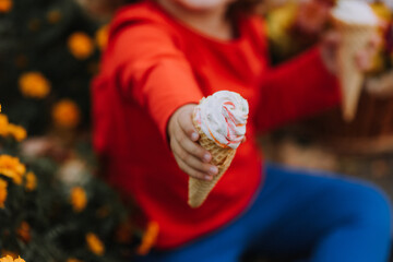 cute curly little girl eating ice cream in park fall time, autumn, card, flowers, banner