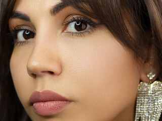 Beautiful brunet model woman face with green eyes and perfect make-up make smile on camera. Portrait of beauty with natural lips and eyes liner, thick eyesbrow . Female face with clear skin close-up.
