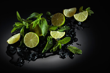 Slices of lime, mint leaves, and ice pieces on a wet black background.