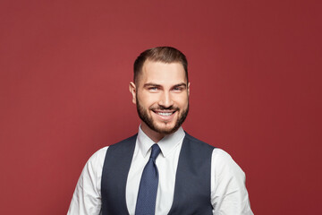 Portrait of young smiling cheerful businessman on red background