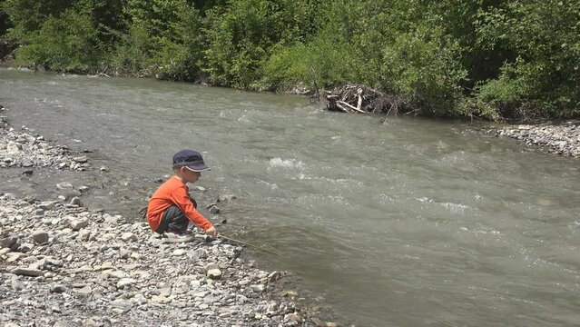 Little child playing on a mountain river bank