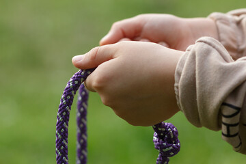 Purple polyamide gymnastic rope in children's hands, close-up. Selective focus.