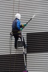 Industrial climber with washing equipment at a height washes the facade of a building with water pressure.
