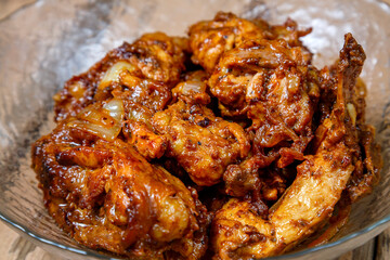 Chicken baked in spices in a glass plate on the table.