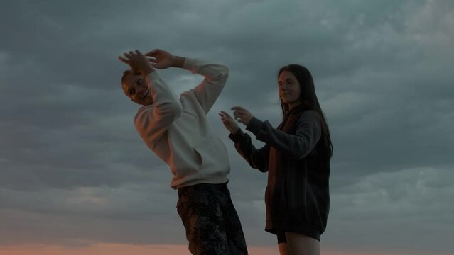 A guy and a girl are standing and fooling around on a motor boat at sunset. Romantic atmosphere.