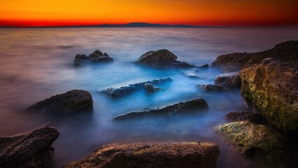 Widok skał oblewanych przez morze o wschodzie słońca przy kolorowym niebie