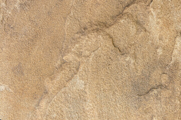 Stone background of sand color with real patterns of spots and scratches close-up. Stone real wall.