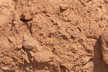 Stone wall is sand colored with real protruding stones from wall. Stone textured background of sand color with stones from wall.