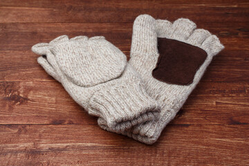 Fototapeta na wymiar Warm woolen gloves lie on a wooden brown table, soft focus.