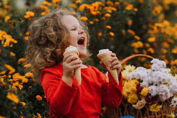 cute curly little girl eating ice cream in park fall time, autumn, card, flowers, banner