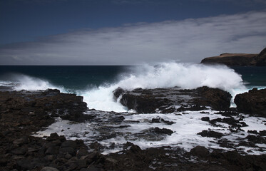 Gran Canaria, north west coast around natural swimming pools Salinas de Agaete, 
waves breaking against old eroded dark lava platform