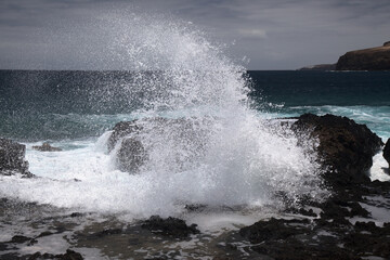 Gran Canaria, north west coast around natural swimming pools Salinas de Agaete, 
waves breaking against old eroded dark lava platform