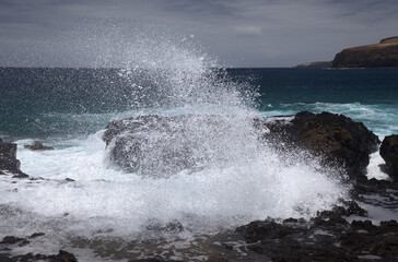 Gran Canaria, north west coast around natural swimming pools Salinas de Agaete, 
waves breaking against old eroded dark lava platform