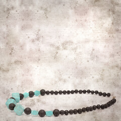 square stylish old textured paper background with necklace made of black volcanic lava beads