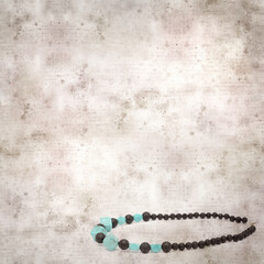 square stylish old textured paper background with necklace made of black volcanic lava beads
