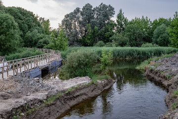bridge construction site over small river in Latvia. Temporary wooden pedestrian bridge over the river