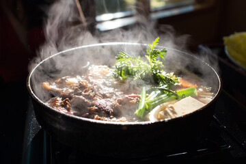 a steaming dish of meat and vegetables