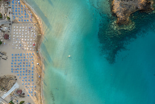 Beach umbrellas in a row at fig tree bay beach Protaras Cyprus. Summer vacations holiday resort.
