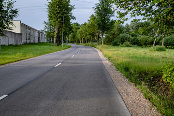 Fototapeta na wymiar new winding asphalt road near abandoned industrial district in Latvia, Jelgava town 