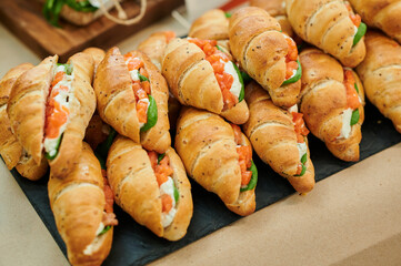 Croissant soft cheese sandwiches with salmon and fresh basil on the table