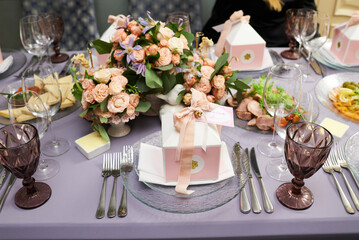 Gift boxes on a plate for guests on a served table for a holiday decorated with rose flowers