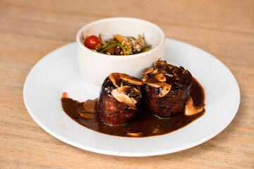 Filet Mignon steaks with a mushroom sauce and a bowl of colorful vegetables
