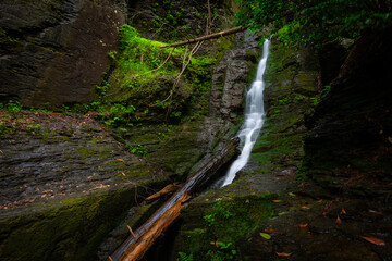 Silverthread narrow waterfall slow shutter speed in forest flowing down rocks with green moss...