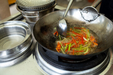 red and green peppers are fried in oil in a frying pan