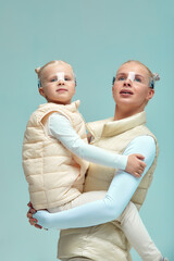 Virtual technology. Happy delighted nice girl smiling and looking at camera while mother holding in her arms wearing digital virtual glasses on biege background