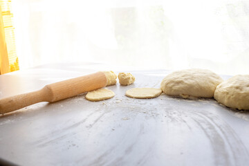 The concept of homemade pies or pizza. On the table is dough, rolling pin and flour. Solar Glare