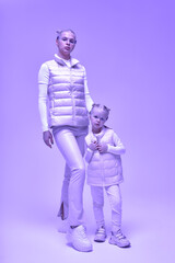 Fototapeta na wymiar Wearable technology concept. Young woman with her little daughter in a white high-tech clothes wearing smart glasses. Smart glasses. Virtual reality.