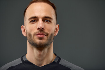 Obraz premium Studio male portrait of handsome powerful athletic man model with healthy muscular body in fashionable black tank top mock up poses on a gray background