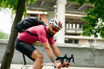 Naklejka premium Caucasian handsome young man in protective helmet goes out for bicycle ride through city streets on blurred background. Cyclist male ride bike outdoors in urban.
