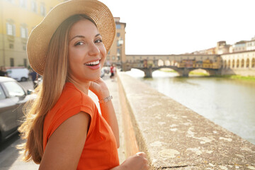 Fototapeta na wymiar Close-up portrait of attractive young tourist woman who turns around and looking at camera on sunset in Florence, Italy
