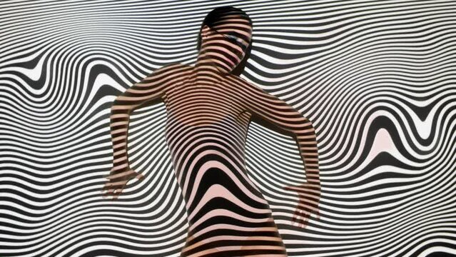 Slim young female model in flesh color bodysuit and blue eye glasses dancing seductively moves slowly overlay with black and white lines stripes twisted motion background. Abstract hypnotic backdrop