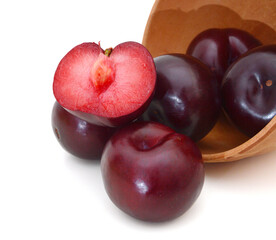 Red plum fruit isolated in wooden bowl on white background