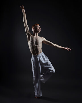 red-haired male dancer demonstrates the choreographic elements of the dance. photo shoot in the studio on a dark background © Vadzim