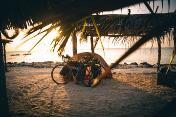 camping bike packing on tropical sandy beach during scenic stunning sunset 