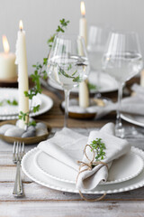 Rustic zero waste wedding decor with natural elements. Wooden table, candles, linen napkins, branches with green leaves. Eco-friendly decoration for the special dinner. Romantic and cozy place