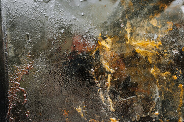 Texture, background, top view of a black tray smeared in fat, oil, pieces of old meat, after cooking. Photography, abstraction.