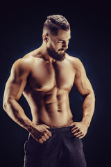 Fototapeta na wymiar Naked strong man showing his abs muscles on dark background. Strength and motivation