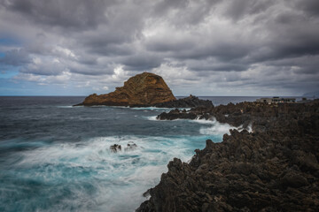 Fototapeta na wymiar Beautiful nature landscape with Atlantic Ocean and lava rock natural swimming pools in Porto Moniz, Madeira, Portugal. Long exposure picture, october 2021.