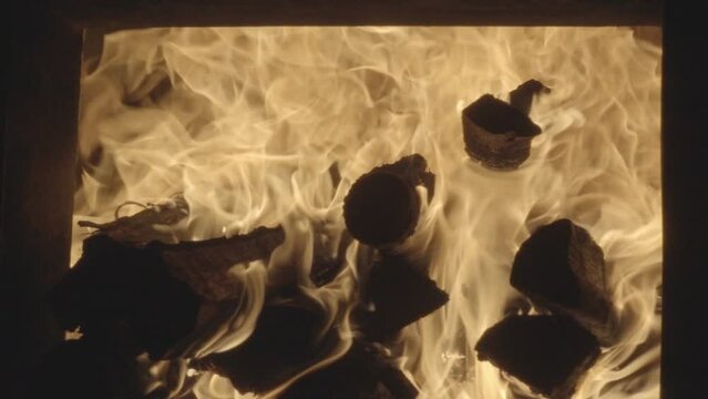 slow motion burning woods in wood fire oven and close up shot of male person throwing wood in oven